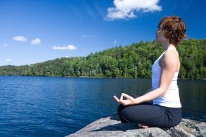 Woman meditating near a lake