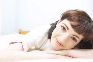 Woman smiling with head resting on hands