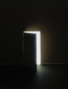 Door opening in darkness, revealing light