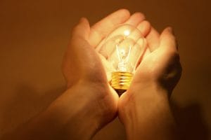 Lit lightbulb cupped in two hands